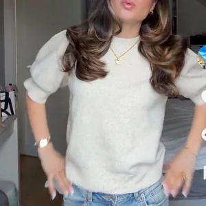 Beige stickad tröja med puffärm - Superfin beige stickad tröja med puffiga ärmar och rund hals. Perfekt att styla med jeans för en chill men ändå trendig look. Mjuk och skön, passar dig som gillar en enkel men snygg stil.