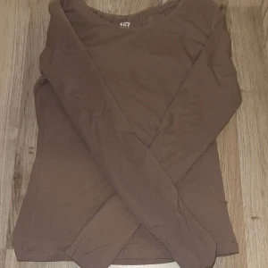 Brun långärmad tröja från 157 - En basic brun långärmad tröja från 157 med rund halsringning. Tröjan är i mjuk bomull och har en enkel, slim passform som funkar till många olika stilar. Perfekt att ha som lager eller bara som den är.