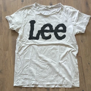 Vit Lee t-shirt med stor logga - Vit t-shirt från Lee i mjuk bomull med stor svart Lee-logga framtill. Klassisk rund hals och korta ärmar. Perfekt basic-plagg med streetkänsla och enkel stil.
