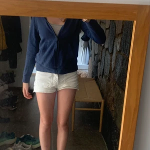 Mörkblå hoodie från H&M - Mörkblå hoodie från H&M med dragkedja framtill och huva. Tröjan har långa ärmar, ribbade muddar och är i mjuk bomullsmix. Perfekt för chill dagar eller när du vill ha något bekvämt och enkelt.