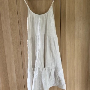 Vit sommarklänning från Gina Tricot - Luftig vit klänning från Gina Tricot i storlek XS. Klänningen har tunna axelband, volang nertill och en avslappnad passform. Perfekt för varma dagar med sitt lätta bomullsmaterial och enkla, stilrena look.