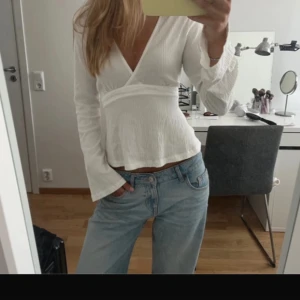 Vit omlottopp från Gina Tricot - Supersnygg vit omlottopp från Gina Tricot med långa ärmar och knyt i midjan. Använd fåtal gånger och finns i svart som är samma skick och storlek!