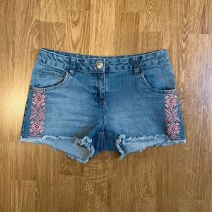 Lowwaist jeansshorts - Lågmidjade blå jeansshorts med broderi på sidorna från pepperts i storlek 152 men skulle säga att de sitter som en xs ungefär, då de är lite för små för mig som annars har s