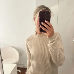 Beige ribbstickad 100% kashmirtröja H&M - Supermjuk och ribbstickad beige tröja i kashmir från H&M. Tröjan har en högre halsringning och långa ärmar, perfekt för lager på lager. Enkel och stilren design som är lätt att matcha med allt. Säljes i storlek S.