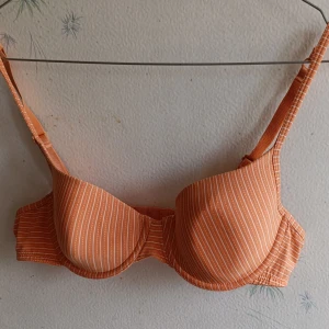 2 behåar i korall färg, 75B - 1 korallfärgad behå med vita ränder och justerbara axelband. 1 korallfärgad behå med justerbara och avtagbara axelband. Perfekt för plagg med urringning. Båda behåar har bygel för stöd och form. Skick som på bilder. 