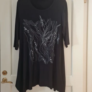 Dam tunika i storlek 48/50 - A-formad tunika med ledig passform över höfterna. Tunika har utsmyckningar framme. Storlek 48/50