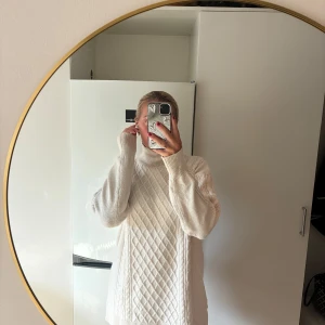 Vit stickad polotröja med mönster - Säljer en oversized vit stickad polotröja med snyggt rutmönster framtill. Tröjan har långa ärmar med bred mudd och hög polokrage som ger en mysig vibe. Perfekt för lager-på-lager och chill höst- och vinterdagar.