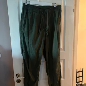 Gröna mjukisbyxor med snörning - Snygga gröna mjukisbyxor med elastisk midja och snörning. Byxorna har avslappnad passform och är perfekta för chill dagar. Tillverkade i ett lätt och mjukt material som känns skönt mot huden.