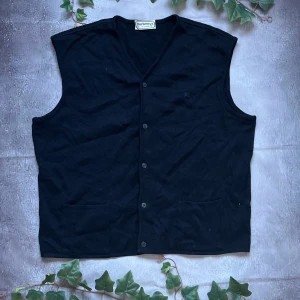 Burberry Merino väst - Säljer denna fina och stiliga internationella Burberry västen för bara 499kr! Otroligt billigt pris för Burberry!  🎨 Färg: Riktig mörkblå, nära svart 📏 Storlek: Burberry storlek 10 vilket motsvarar XL 📐 Mått: Längd - 68cm, Axelbredd - 48cm ♻️ Skick: 9/10 utan defekt eller fläckar på utsidan. Bara liten fläck på taggen men inget som syns  🧵 Material: 60% Lana Merino, 40% Acrilico  ‼️Skickas dagen efter köpet genomförs‼️
