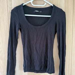 Svart ribbad långärmad tröja Bik Bok - Svart långärmad tröja från Bik Bok i storlek XS. Tröjan är ribbad med rundad, djup urringning och sitter tajt mot kroppen. Perfekt att styla med jeans eller kjol för en clean look.