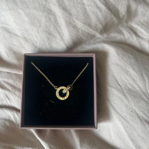 Guldigt halsband från Edblad - Snyggt halsband från Edblad med tunn guldfärgad kedja och rund cirkelberlock dekorerad med små gnistrande stenar. Perfekt för att ge din outfit lite extra bling. Kommer i originalask.