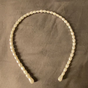 Diadem med pärlor i vit nyans - Snyggt diadem täckt med vita pärlor i olika former. Perfekt accessoar för att ge en elegant touch till din look. Pärlorna är glansiga och sitter tätt längs hela diademet. Passar dig som vill sticka ut med en klassisk men trendig stil.