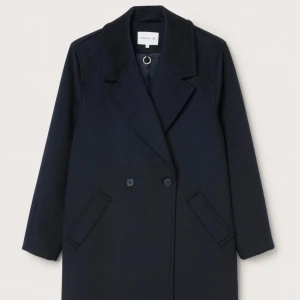 Marinblå kappa från MQ STOCKH LM Studio - Naomi coat är en oversize kappa med moderna snitt från Stockhlm Studio, tillverkad i en mjuk ullmix-kvalité med vacker lyster. Volumiös, cocoonformad passform. Kappan är dubbelknäppt, har krage och slag, högt sprund bak samt fickor i sidan. Foder i viskos och återvunnen polyester. Marinblå. Slutsåld! 