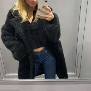 Svart teddykappa med oversized passform - Säljer en svart teddykappa med oversized fit och stora slag. Jackan är fluffig och mjuk, perfekt för kalla dagar. Den har lång ärm och går ner över höfterna. Enkel att styla till både jeans och kjol. Supermysig och trendig look!