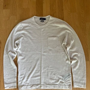 Beige cashmere tröja Polo Ralph Lauren - Supermjuk beige tröja i 100% kashmir från Polo Ralph Lauren. Klassisk rund hals, långärmad och med en liten bröstficka. Perfekt för dig som gillar stilren och lyxig känsla. Passar dig som vill ha en enkel men exklusiv look.