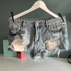  jeansshorts med nitar - Ett par snygga ljusblåa jeansshorts med storlek 40 men tycker de är mer som 38!! Kommer ej ihåg vart ifrån eftersom det var så länge sen. Använd 2-3 gånger!💘