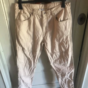 Beige byxor - Snygga beige byxor med klassisk femficksdesign och markerade sömmar vid knäna. Byxorna har normal passform och är tillverkade i mjuk bomull, perfekta för en avslappnad och stilren look.