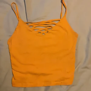 Gul croppad linnetopp från FB Sister - Snygg gul croppad linnetopp från FB Sister i storlek XS. Toppen har tunna axelband och cool snörning framtill som ger en trendig look. Perfekt för varma dagar och att styla med höga jeans eller kjol.