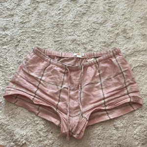 Rosa rutiga pyjamasshorts från Gina Tricot - Snygga rosa pyjamas shorts från Gina Tricot med rutigt mönster i vitt och grått. De har elastisk midja och är tillverkade i mjuk bomull, perfekta för varma dagar. Passformen är normal och de är riktigt bekväma att ha på sig.