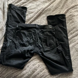 Svarta jeans från Crocker, 25/32 - Svarta jeans från Crocker i klassisk femficksmodell. Jeansen har dragkedja och knapp framtill, bootcut men nästan raka och diskreta sömmar. Materialet är jeans med en något matt finish. Rätt så använda men fortfarande skitsnygga önskar att dom fortfarande passa mig! Lite för små i midjan.