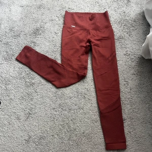 Rosa seamless tights Aim'n  - Säljer ett par rostfärgade seamless tights från Aim'n i storlek XS. De har hög midja, ribbade detaljer och snygg struktur på benen. Materialet är stretchigt och består av polyamid och elastan, perfekt för träning eller chill.