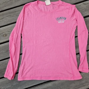 Rosa långärmad tröja från Champion - Säljer en rosa långärmad tröja från Champion med tryck på bröstet. Modellen är enkel med rund halsringning och normal passform.