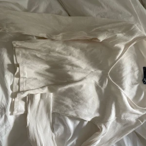 Vit ribbad långärmad tröja 157 - Säljer en vit långärmad tröja från 157 med snygg ribbad struktur och v-ringad hals. Tröjan är i mjukt material och har en clean, enkel look som passar perfekt till jeans eller kjol. Perfekt för dig som gillar stilrena basplagg.
