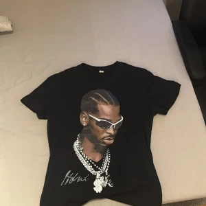 Svart t-shirt med tryck på sga  - Svart t-shirt i bomull med stort tryck på SGA på framsidan. T-shirten har korta ärmar, rund hals och coolt motiv med kedjor och signaturdetaljer. Perfekt för dig som gillar streetstyle och vill sticka ut med en unik look. Hör av er vid funderingar pris kan diskuteras 