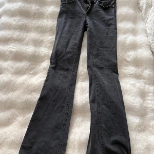 Grå bootcut jeans från 157 - Snygga grå jeans från 157 med klassisk femficksmodell och bootcut-ben. Jeansen har normal midja och är tillverkade i mjukt denimtyg med dragkedja och knapp framtill. Perfekta för dig som gillar en avslappnad men trendig look.
