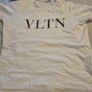 Vit VLTN t-shirt från Valentino - Pris kan diskuteras. Den blev skrynklig i paketet när jag köpte den från en annan människa. Men jag kommer såklart stryka den och tvätta den innan jag säljer den. Leverar så fort som möjligt.Snygg vit t-shirt från Valentino med svart VLTN-tryck på bröstet. Klassisk rund halsringning och korta ärmar. Tillverkad i mjuk bomull som känns skön mot huden. Perfekt för dig som gillar stilrena designer och vill ha en ikonisk logga på din tee.