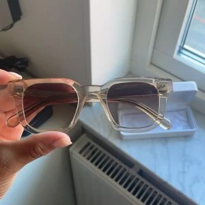 CHIMI solglasögon  - Snygga solglasögon från CHIMI med fyrkantig form och transparent beige båge. Glasen är mörktonade och ger en cool vibe. Kommer med originalfodral. Perfekta för att lyfta din stil i sommar!