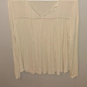 Krämvit blus från Mango med knyt - Luftig och flowy krämvit blus från Mango med långa ärmar och snygg knytning vid halsen. Tunt, lätt material med fina sömdetaljer och avslappnad passform. Perfekt för dig som gillar en bohemisk och chill vibe.