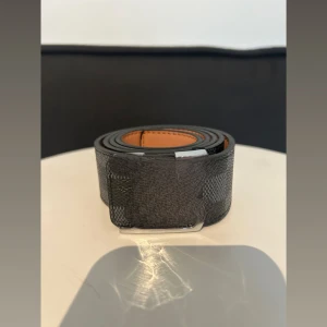 Svart rutigt skärp med silverfärgat spänne - Snyggt svart bälte med rutigt mönster och stilrent silverfärgat spänne. Insidan är ljusbrun och bältet är gjort i skinn med en exklusiv känsla. Perfekt accessoar för att lyfta din outfit med en modern touch. 105 cm långt skriv om du vill ha bättre bilder!