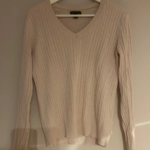 Ljusrosa kabelstickad tröja Tommy Hilfiger - Supersnygg ljusrosa kabelstickad tröja från Tommy Hilfiger med v-ringning och långa ärmar. 