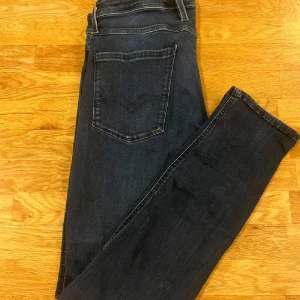 Mörkblå Replay jeans, storlek 32/32 - Snygga mörkblå jeans från Replay i klassisk femficksmodell. Jeansen har raka ben och normal passform, med diskreta slitningar och tydliga sömmar. Perfekta för dig som gillar stilrena och tidlösa jeans med en modern touch.