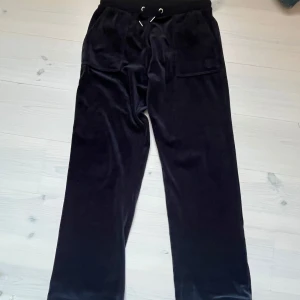 Svarta velourbyxor Juicy Couture - UPPSYDDA NÅGRA CM!! Mörkblå mjukisbyxor från Juicy Couture i mjuk och glansig velour. Byxorna har bred resårmidja med snörning, raka ben och stora fickor framtill. 