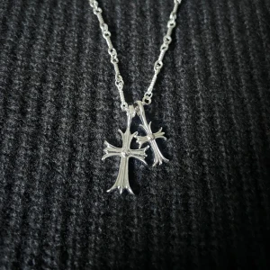 Croix Jumelée – Dual Cross Necklace - Två kors med dubbelsidig design – slät på ena sidan, stenprydd på den andra. 43 + 5 cm kedja med justerbar passform – kan fästas var som helst längs länken.