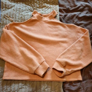 Stickad peach offshoulder-tröja Gina Tricot - Superfin stickad tröja i peach/ljusrosa från Gina Tricot. Tröjan har offshoulder-design med hög krage och långa ärmar. Mjuk och skön, perfekt för lager-på-lager under höst och vinter. Passar dig som gillar en chill men ändå trendig vibe.