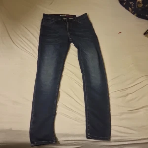 Mörkblå skinny jeans Hybrid - Snygga mörkblå skinny jeans från Hybrid med klassisk femficksdesign och lätt slitna detaljer på låren. Jeansen har normal midja och smal passform hela vägen ner. Perfekta för dig som gillar en stilren och modern look.