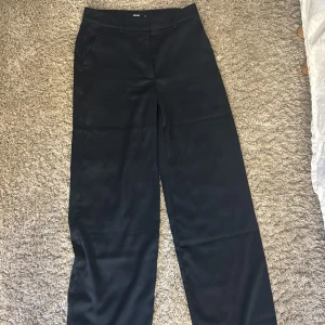 Svarta kostymbyxor från BikBok - Snygga svarta kostymbyxor från BikBok i rak och lite vidare modell. Byxorna har klassisk design med hällor för bälte och sidfickor. Perfekta för en clean och stilren look.