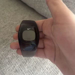 Svart digital sportklocka från Nike - Cool svart digital sportklocka från Nike med stilren och futuristisk design. Klockan har ett brett armband i plast och en digital display med Nike-loggan på framsidan. Perfekt för dig som gillar en clean och sportig look. SJUKT RARE