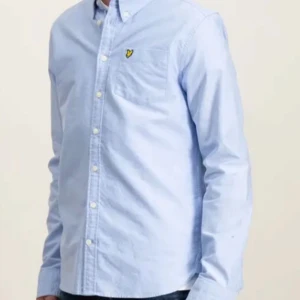 Ljusblå skjorta från Lyle & Scott - Snygg ljusblå skjorta från Lyle & Scott med klassisk krage och vita knappar. Bröstficka med den ikoniska gula fågeln broderad. Skjortan är långärmad och i mjuk bomull, perfekt för en clean och stilren look.pris kan diskuteras vid snabb affär. Helt ny ( använd 1 gång cirka 2 timmar ) . Nypris cirka 650 och säljer för endast 450 😀😊