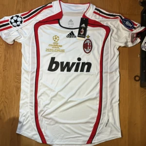 AC Milan Champions League 2007 Maldini - Säljer min nya AC Milan bortatröja från Champions League-finalen 2007 i Aten, med Maldini och nummer 3 på ryggen. Vit med röda och svarta detaljer, broderade märken och guldtext. Bwin sponsortryck och Champions League-patch på ärmen. Tillverkad i lätt polyester. Priset kan diskuteras vid snabb affär.