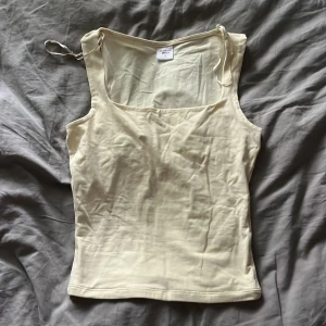 Ljusgul linne topp  - Enkel och stilren ljusgul linnetopp med fyrkantig ringning och lite tjockare axelband. Perfekt för varma dagar och lätt att matcha med jeans eller kjol. Mjuk och skön känsla tack vare bomullsmaterialet. Andvänt 1 gång