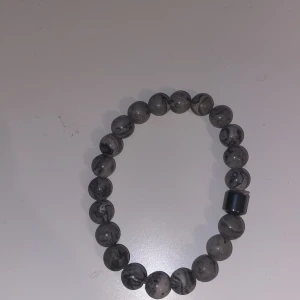 Armband - Ett elegant och stilrent armband bestående av runda pärlor i grå svart marmorerad sten