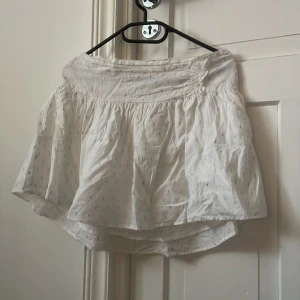 Vit kortkjol med guldprickar Gina Tricot - En vit kjol med guldiga detaljer, från Gina Young. Använd få gånger.