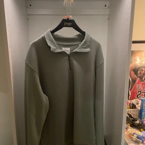 Grå half zip tröja från Jack & Jones - Snygg grön långärmad tröja från Jack & Jones med half zip och hög krage. Oversized fit för en chill vibe. Perfekt till jeans eller mjukisbyxor. Mjuk bomullskänsla och enkel att matcha med det mesta. Aldrig använd