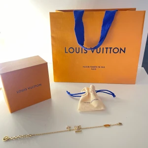 Armband från Louis Vuitton - Snyggt och stilrent armband från Louis Vuitton i guldtonad metall. Kedjan är tunn och har detaljer som LV-logga och små berlocker (gjort av glas) i ljusrosa. Kommer med originalpåse och ask, perfekt för dig som gillar exklusiva accessoarer. Priset kan diskuteras vid en snabb affär 🩷 