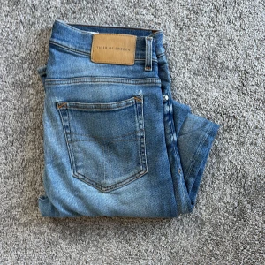 Blå jeans från Tiger of Sweden 32/32 - Snygga blå jeans från Tiger of Sweden med klassisk femficksdesign och ljus tvätt. Jeansen har normal passform och är tillverkade i Italien av mjukt bomullstyg. Perfekta för dig som gillar stilrena och tidlösa jeans.