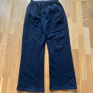 Svarta wide mjukisbyxor Trendyol - Svarta mjukisbyxor från Trendyol med bred passform och resår i midjan. Byxorna har snörning framtill, raka ben och en bakficka med lock. Perfekta för chill dagar eller när du vill ha det extra bekvämt.